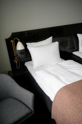 a bed with white sheets and a lamp and a chair at Hotel Skt. Annæ in Copenhagen
