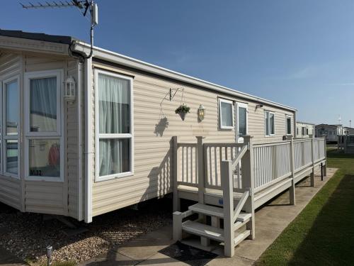 ein großer weißer Wohnwagen mit einer Veranda und einem Haus in der Unterkunft Meadow Lakes 82 - Golden Palm Resort - Meadow Lakes Caravan Hire in Chapel Saint Leonards