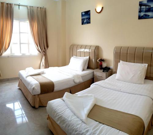 a hotel room with two beds and a window at جزيرة اللؤلؤ للشقق الفندقية PEARL ISLAND HoTEL APARTMENT in Al Buraymī