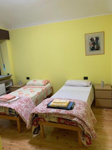 two beds in a room with yellow walls at Le Lanterne in SantʼAntonino di Susa