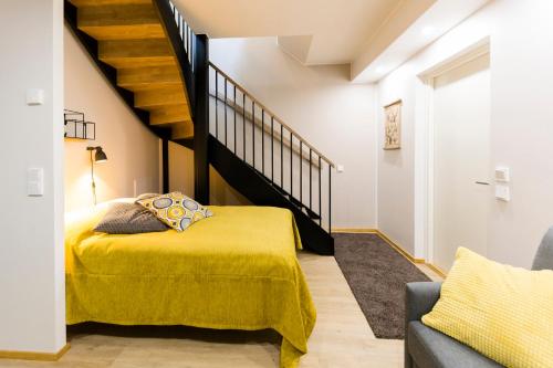 a bedroom with a yellow bed and a staircase at Levin Sirius Apartments Visit Levi in Levi