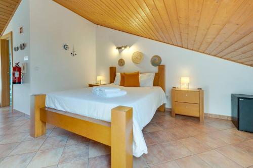 a bedroom with a large bed and a wooden ceiling at Abrigo de Milfontes - Suítes in Vila Nova de Milfontes