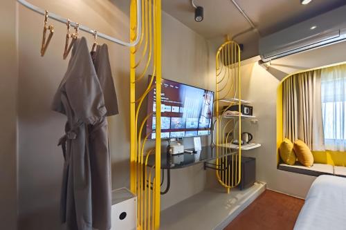 a bedroom with yellow accents and a tv and a bed at CRIMSON SERIES - Boutique Hotel & Wine Bar in Chiang Mai