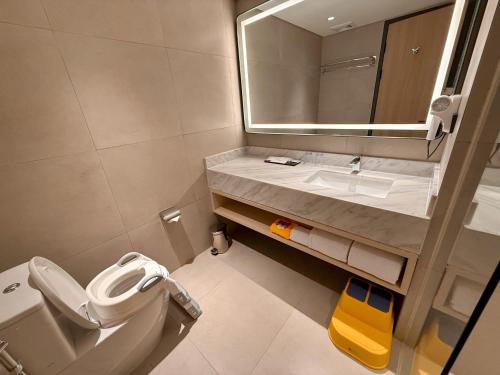 a bathroom with a sink and a toilet and a mirror at FortunaSuites Malioboro Yogyakarta in Sentool