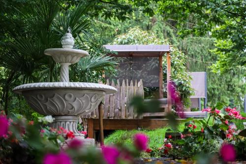a stone fountain in a garden with a gazebo at Das Parkhotel in Bad Wörishofen