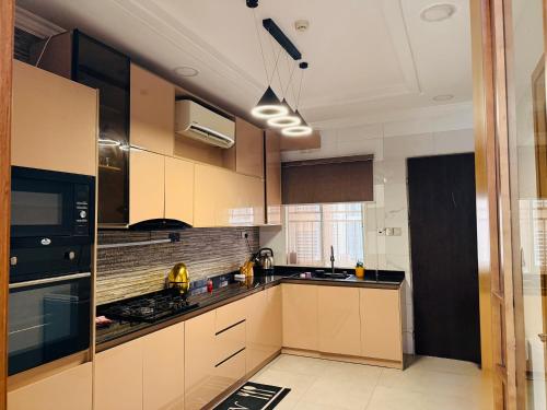 a kitchen with brown cabinets and black appliances at Geodetic Apartment in Lagos