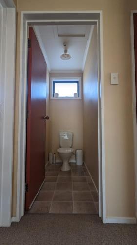 a bathroom with a toilet and a door with a window at Polka Apartment in Ranfurly