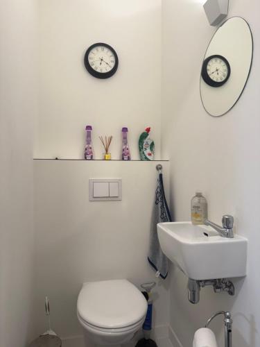 a bathroom with a toilet and a sink and two clocks at Atomium Victory in Brussels