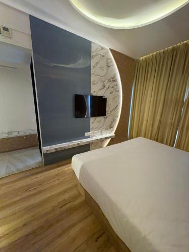 ein Schlafzimmer mit einem Bett und einem Flachbildfernseher in der Unterkunft The Moon Hotel in Nerul
