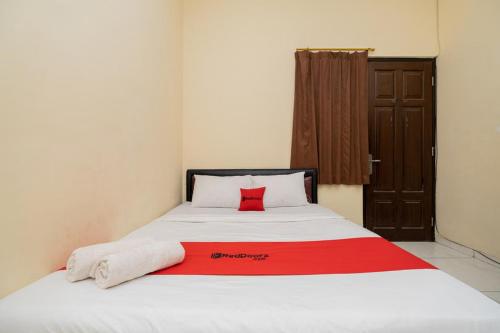 a bed with a red pillow on top of it at RedDoorz At Graha 99 Simomulyo in Surabaya