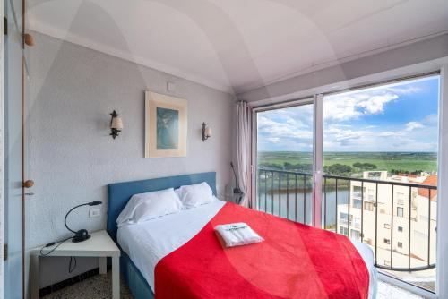 エンプリアブラバにあるAppartement Bord de Mer Karina 1 by Welhomyのベッドと大きな窓のある寝室