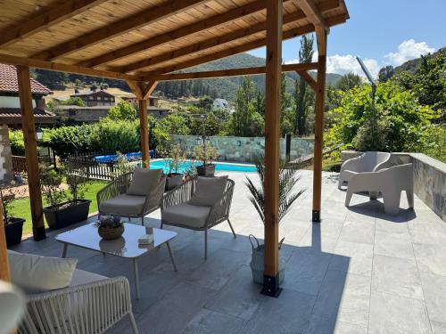 a patio with chairs and a pergola and a pool at Apartamentos Rurales Valverde in Potes