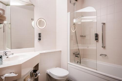 a white bathroom with a toilet and a shower at Leonardo Hotel Aachen in Aachen