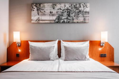 a bedroom with a bed with two white pillows at Leonardo Hotel Aachen in Aachen