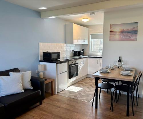 a living room and kitchen with a table and a couch at Modern Airy Chalets on popular California Sands Holiday Park - short walk to beach, Nr Norfolk Broads & Great Yarmouth in Scratby