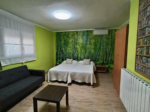 a bedroom with a bed and a couch and a painting at Casa Rural Natalia in Valmuel