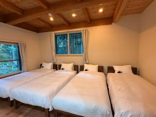a row of four beds in a room at Nishihara Village, Aso District, near the Airport MACOMO in Koga