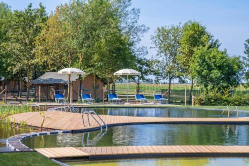 a swimming pool with chairs and umbrellas at Folaghe bilocale in Precenicco