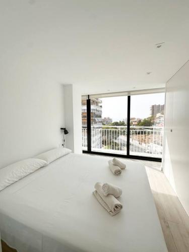 a white bed with two slippers on top of it at Rincón Albufereta Piscina, Sierra y Mar in Alicante
