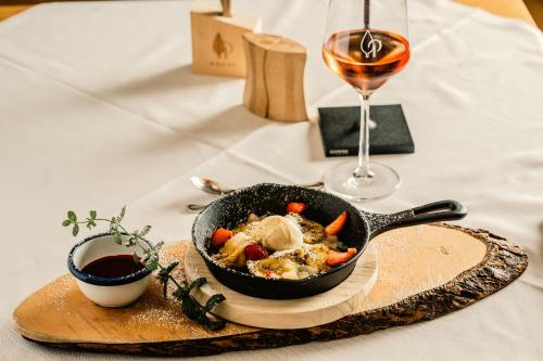 a pan of food on a table with a glass of wine at Das Parkhotel in Bad Wörishofen