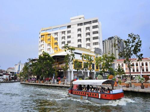 a boat traveling down a river in a city at Sunday Malacca Formerly Tun Fatimah in Malacca
