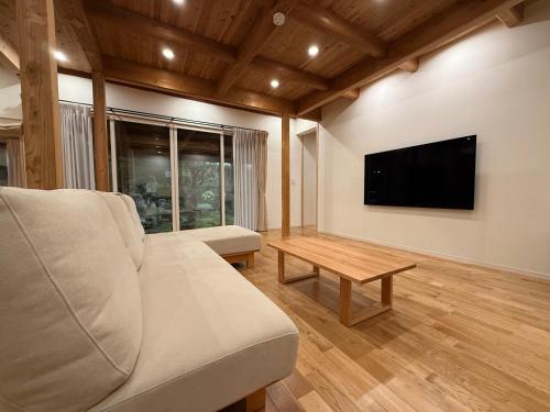 a living room with a couch and a flat screen tv at Nishihara Village, Aso District, near the Airport MACOMO in Koga