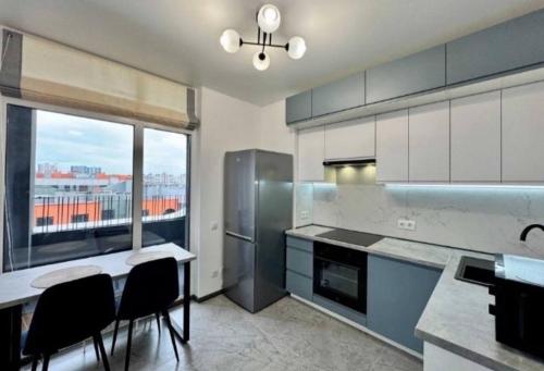 eine Küche mit Tisch und Stühlen und einem großen Fenster in der Unterkunft La familia ЖК республіка 195 in Kiew