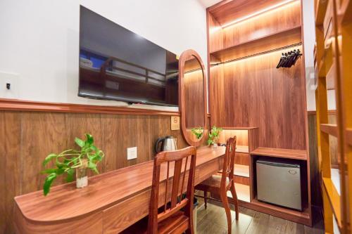 a dining room with a wooden table and a tv at Lotus Hotel Đà Lạt in Da Lat