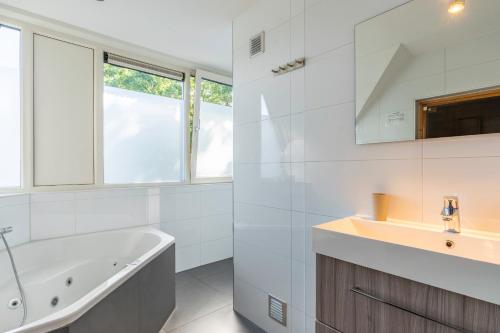 a white bathroom with a tub and a sink at Hoogelandt 126 in De Koog
