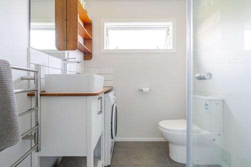 a bathroom with a toilet and a sink and a window at Modern Garden Cottage with Private Outdoor Area - New Lynn in Auckland