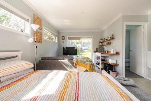 a bedroom with a bed and a living room at Modern Garden Cottage with Private Outdoor Area - New Lynn in Auckland