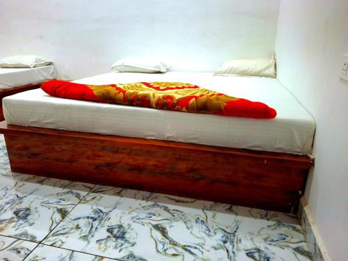 a bed with a wooden frame with a red blanket on it at Shri mukut bihari agrawal dharamshala ,dholi pyau himmat pura tiraha mathura in Mathura
