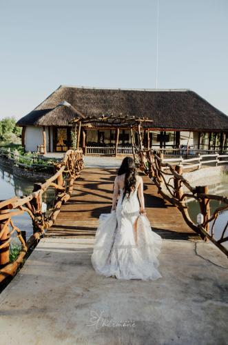 a woman in a wedding dress standing on a bridge at Witgatboom Boskamp in Naboomspruit