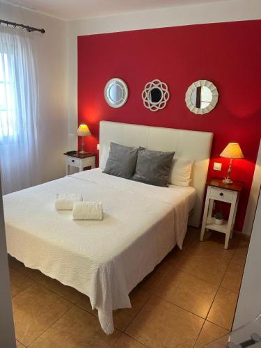 a bedroom with a white bed with a red wall at Margarita House in Arrecife