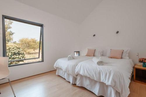 a white bedroom with a bed and a window at Underhill in Corfe Castle