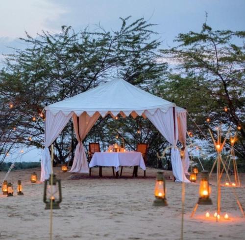 a tent on the beach with a table and lights at The Desert Resort Jaisalmer in Jaisalmer