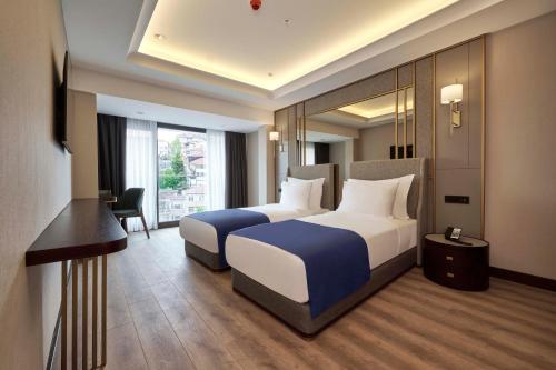 a hotel room with two beds and a desk at Çırağan Hotel Bosphorus in Istanbul