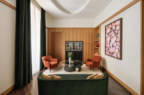 a living room with a green couch and orange chairs at Park Hyatt Milano in Milan