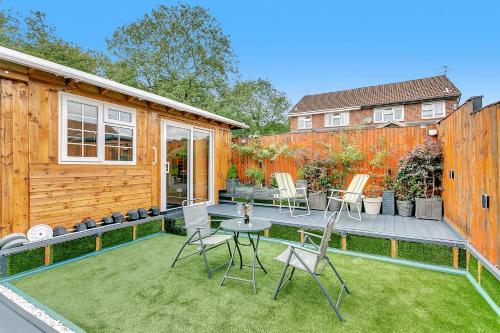 a backyard with a deck with chairs and a table at Aspen Close 4 Bedroom Retreat with Spa, Sauna and Gym in Buckinghamshire