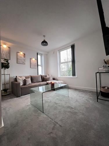 a living room with a couch and a glass table at Modern Luxury Escape Suite In The Heart of Urmston Town Centre in Urmston