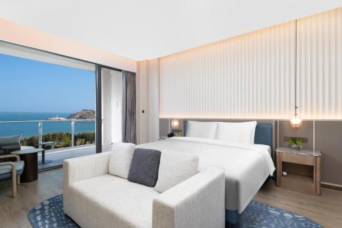 a bedroom with a bed and a couch and a large window at C&D Hotel Dongshan Zhangzhou in Tongling