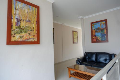 a living room with a black leather chair and a painting at RedDoorz @ Jalan Majapahit Semarang in Alastuwo
