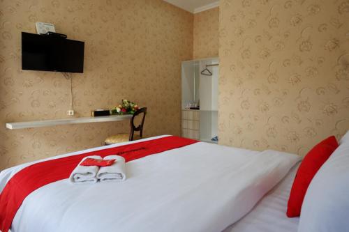 a bedroom with a bed with two slippers on it at RedDoorz @ Jalan Majapahit Semarang in Alastuwo