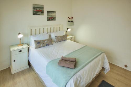 een slaapkamer met een wit bed met een handdoek erop bij Sea Cottage, Langebaan, 4-sleeper in Langebaan