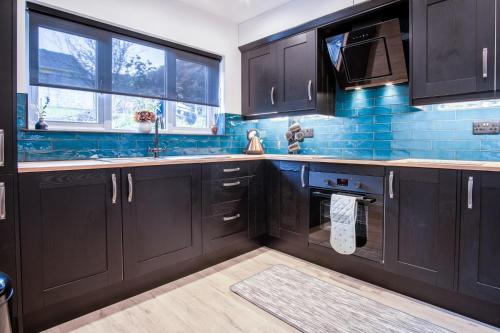 a kitchen with black cabinets and a sink and a window at Wiston Street - 2 Bedroom Holiday Home - Pembroke in Pembroke