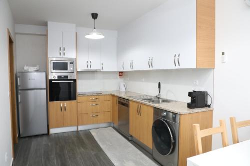 a kitchen with white cabinets and a washer and dryer at Cantinho do Sossego in Miranda do Douro