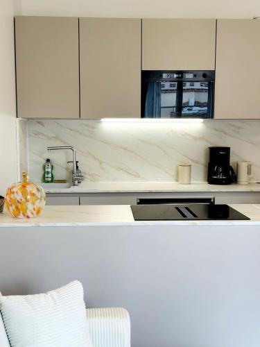 a kitchen with white cabinets and a sink and a couch at La Marquise Rennes Gare in Rennes