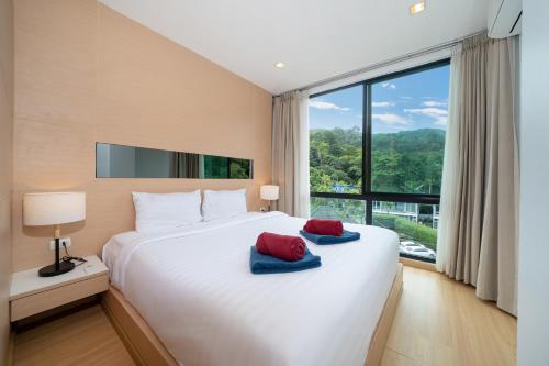 ein Schlafzimmer mit einem großen Bett mit roten und blauen Handtüchern darauf in der Unterkunft Hillside 2BR Apartment with Pool & Gym 5 Min to Kamala Beach 48RK in Kamala Beach