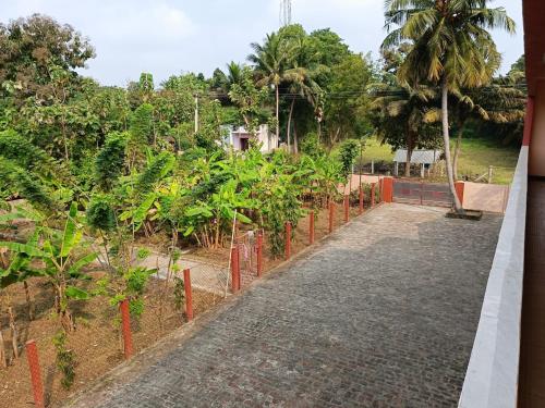 a walkway leading to a garden with trees and palm trees at SV HOMES Thiruvisanallur in Tribhuvanam