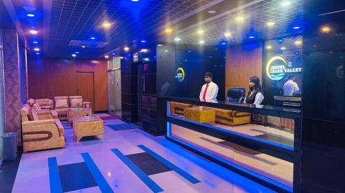 two people standing at a counter in a room at Hotel Park Valley International in Ābdullāpur